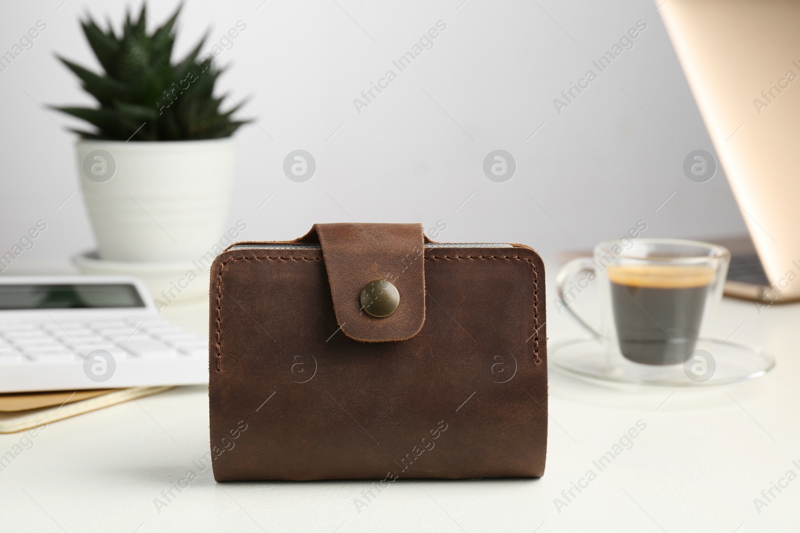 Photo of Leather card holder, calculator and coffee on white table