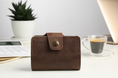 Leather card holder, calculator and coffee on white table