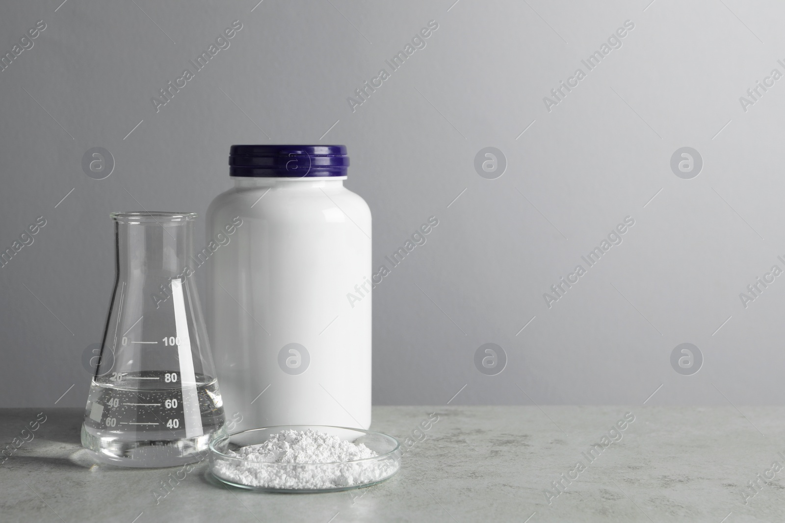 Photo of Petri dish with calcium carbonate powder, jar and laboratory flask on light grey table. Space for text