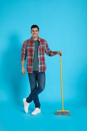 Photo of Man with yellow broom on light blue background