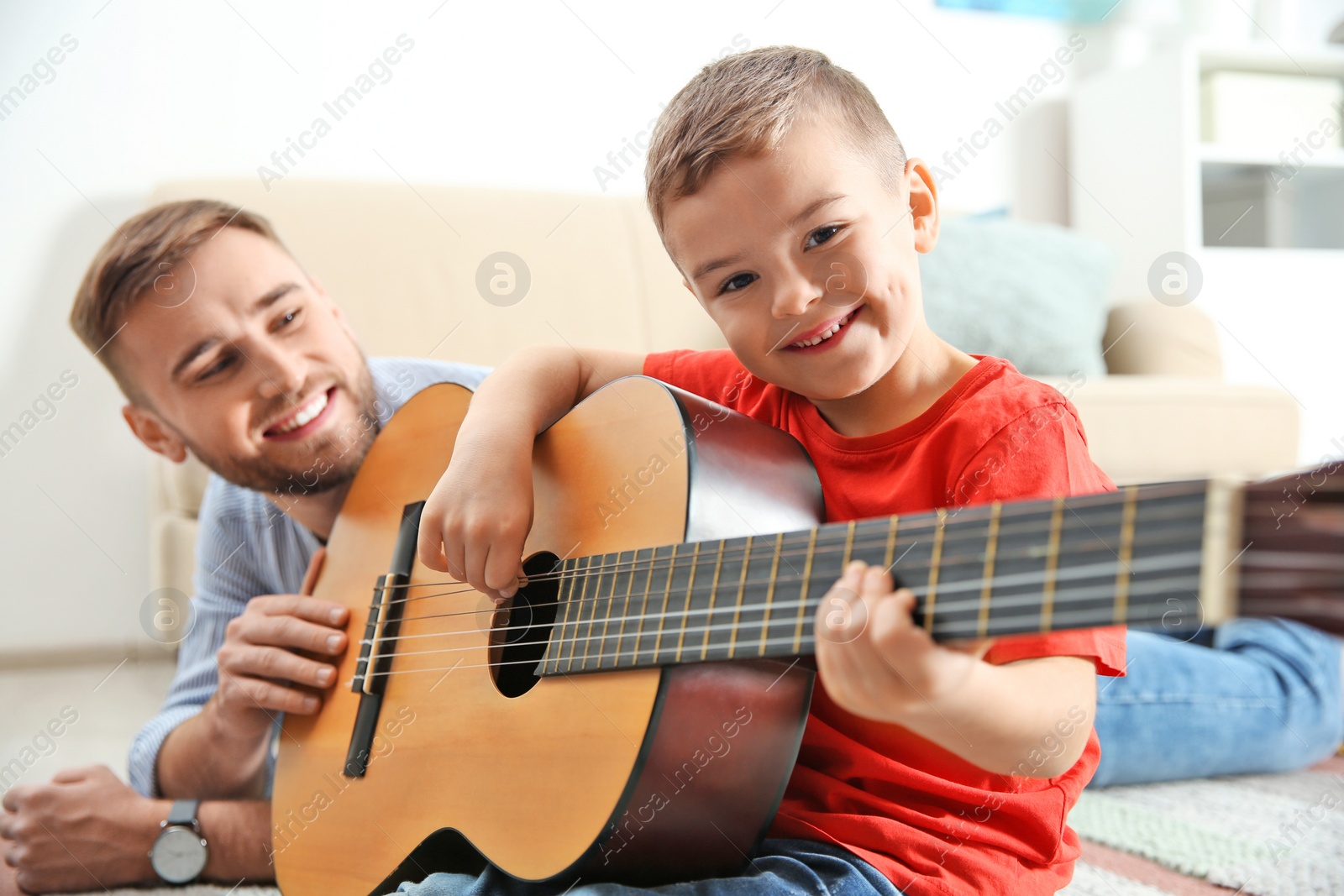 Photo of Father teaching his little son to play guitar at home