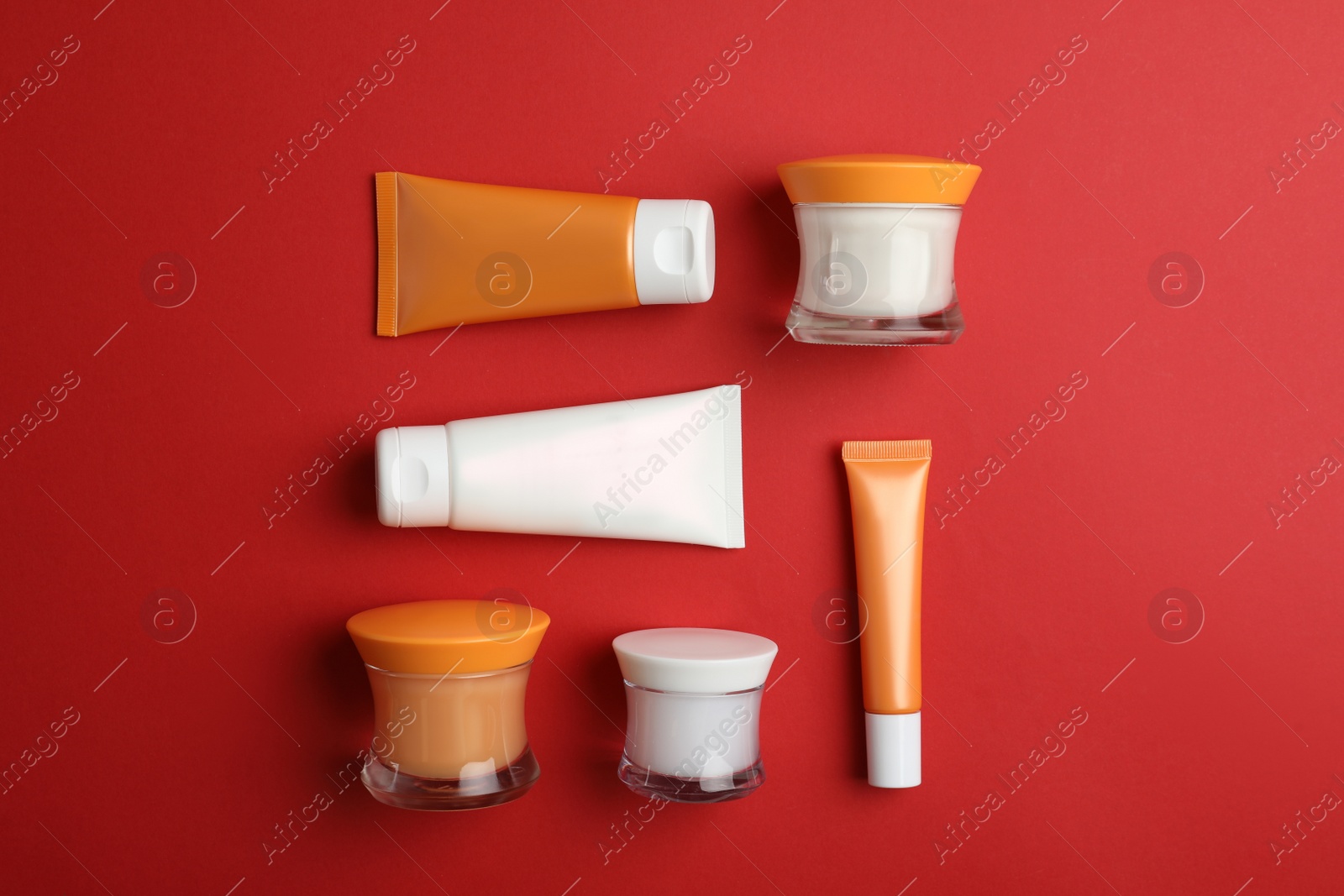 Photo of Set of luxury cosmetic products on red background, flat lay