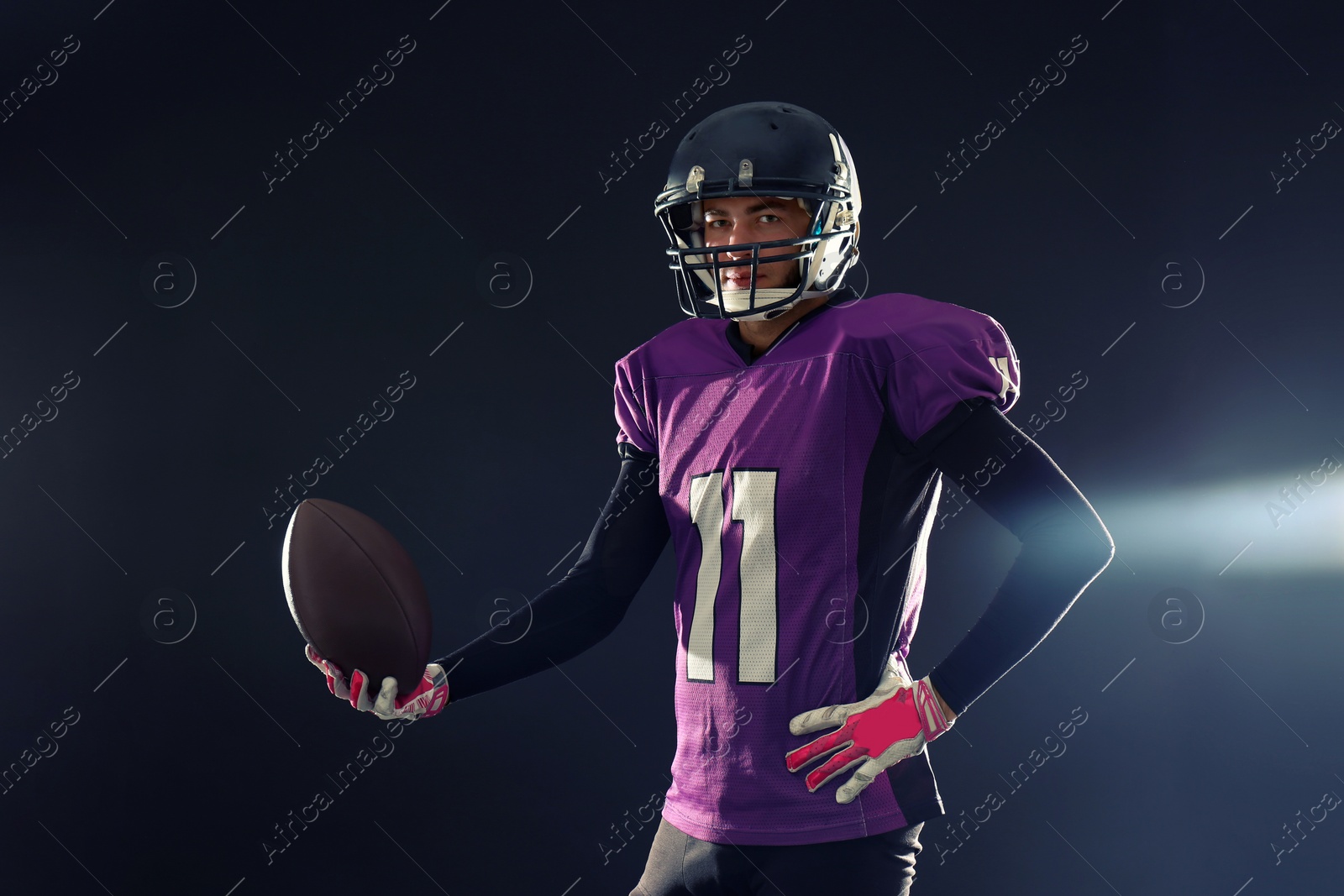 Photo of American football player in uniform on dark background