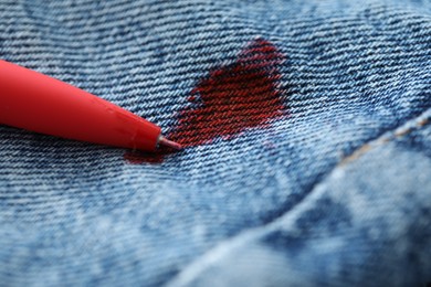 Photo of Pen and stain of red ink on jeans, closeup