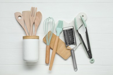 Photo of Set of different kitchen utensils on white wooden table, flat lay