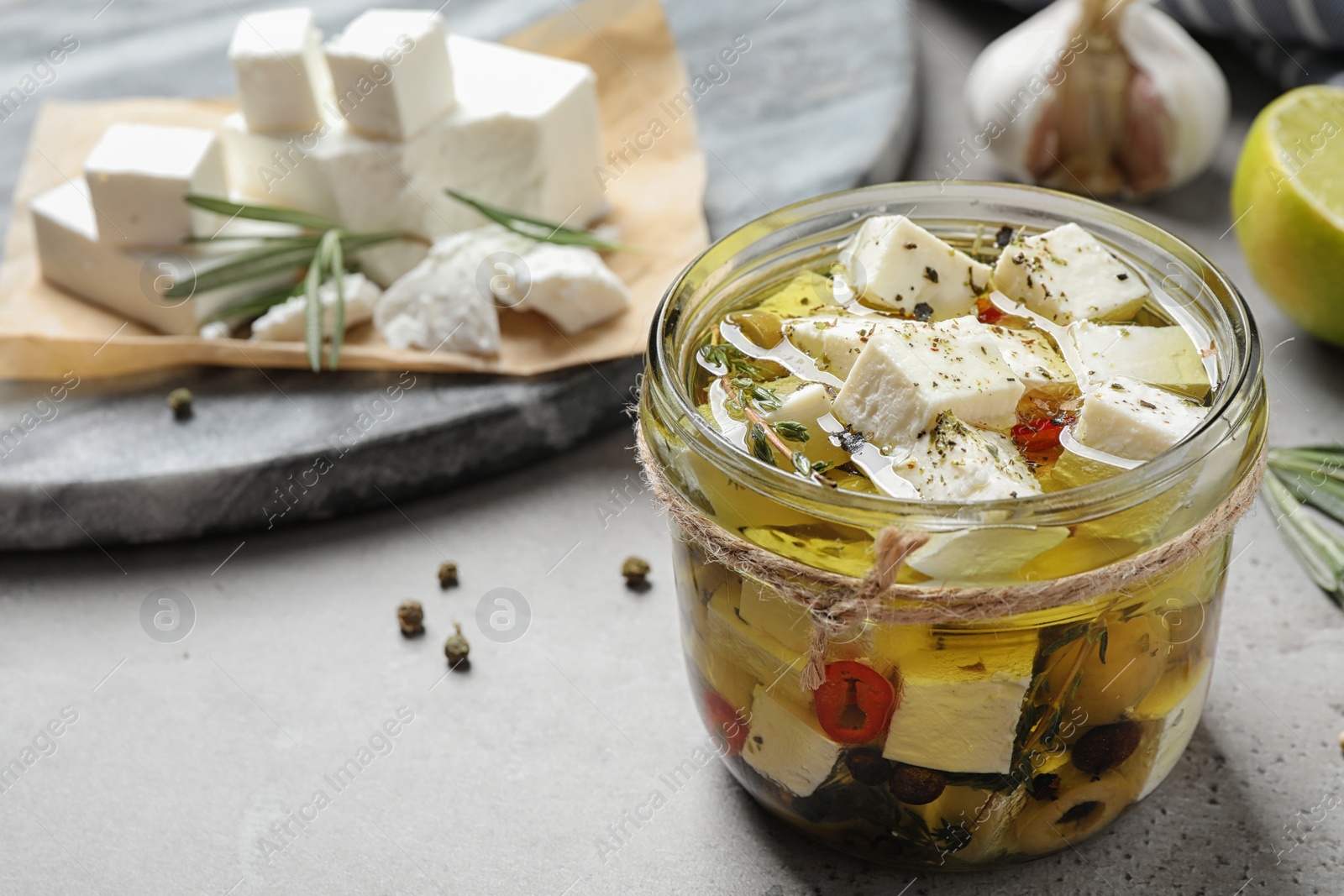 Photo of Composition with pickled feta cheese in jar on grey table, space for text