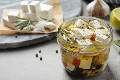 Photo of Composition with pickled feta cheese in jar on grey table, space for text