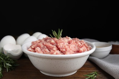 Photo of Raw chicken minced meat with rosemary on wooden table