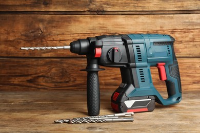 Modern electric power drill with bits on wooden table