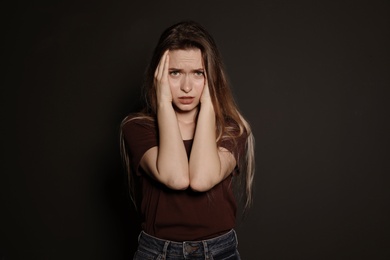 Photo of Portrait of upset young woman on dark background