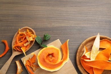 Photo of Dry orange peels on wooden table, flat lay. Space for text