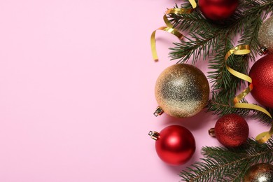Shiny Christmas balls, streamers and fir tree branches on pink background, flat lay. Space for text