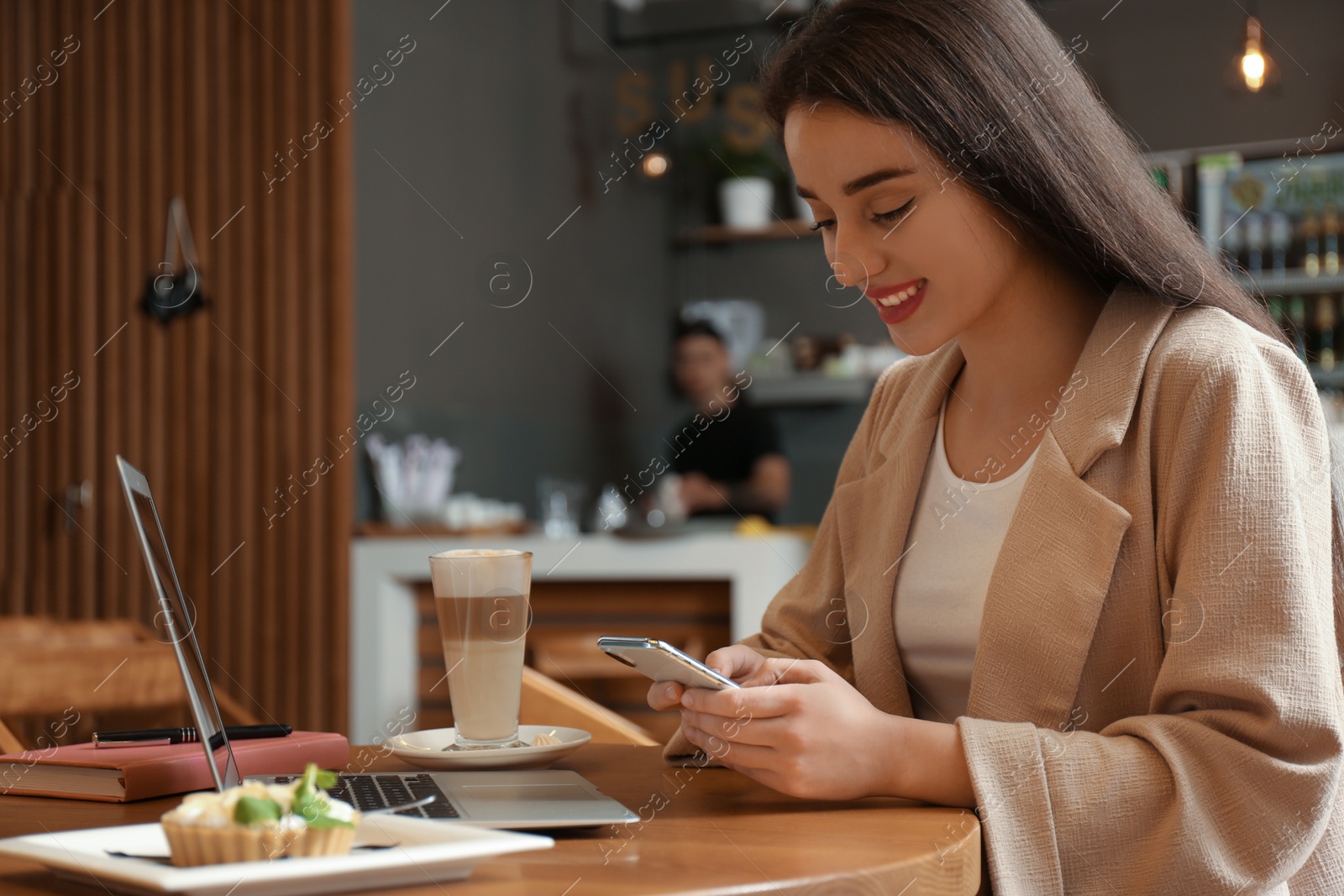 Photo of Young blogger with smartphone and laptop in cafe