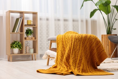 Spring atmosphere. Wooden bench with blanket, houseplant and shelving unit in stylish room