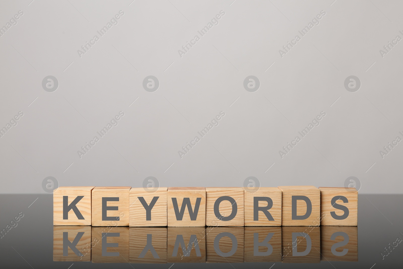 Photo of Wooden cubes with word KEYWORDS on light grey background. Space for text