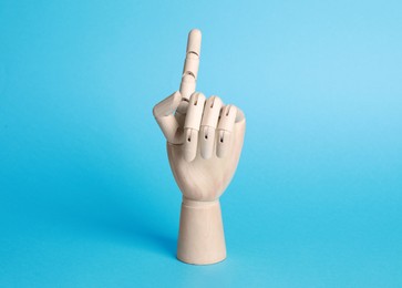 Wooden hand model on light blue background. Mannequin part