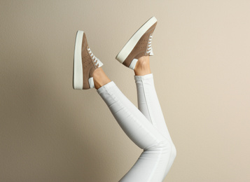 Woman wearing shoes on beige background, closeup