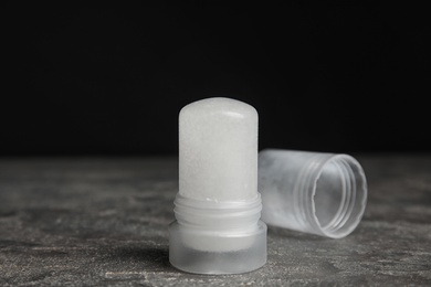 Photo of Natural crystal alum deodorant and cap on grey table against black background