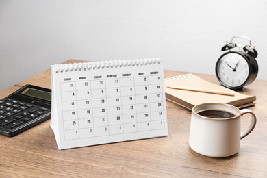 Composition with calendar and cup of coffee on wooden table