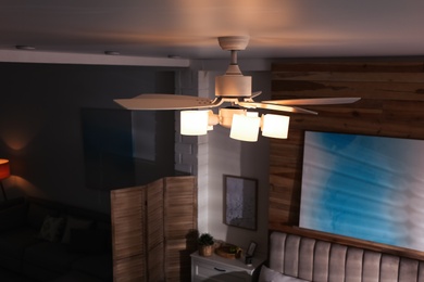 Photo of Modern ceiling fan with lamps in room