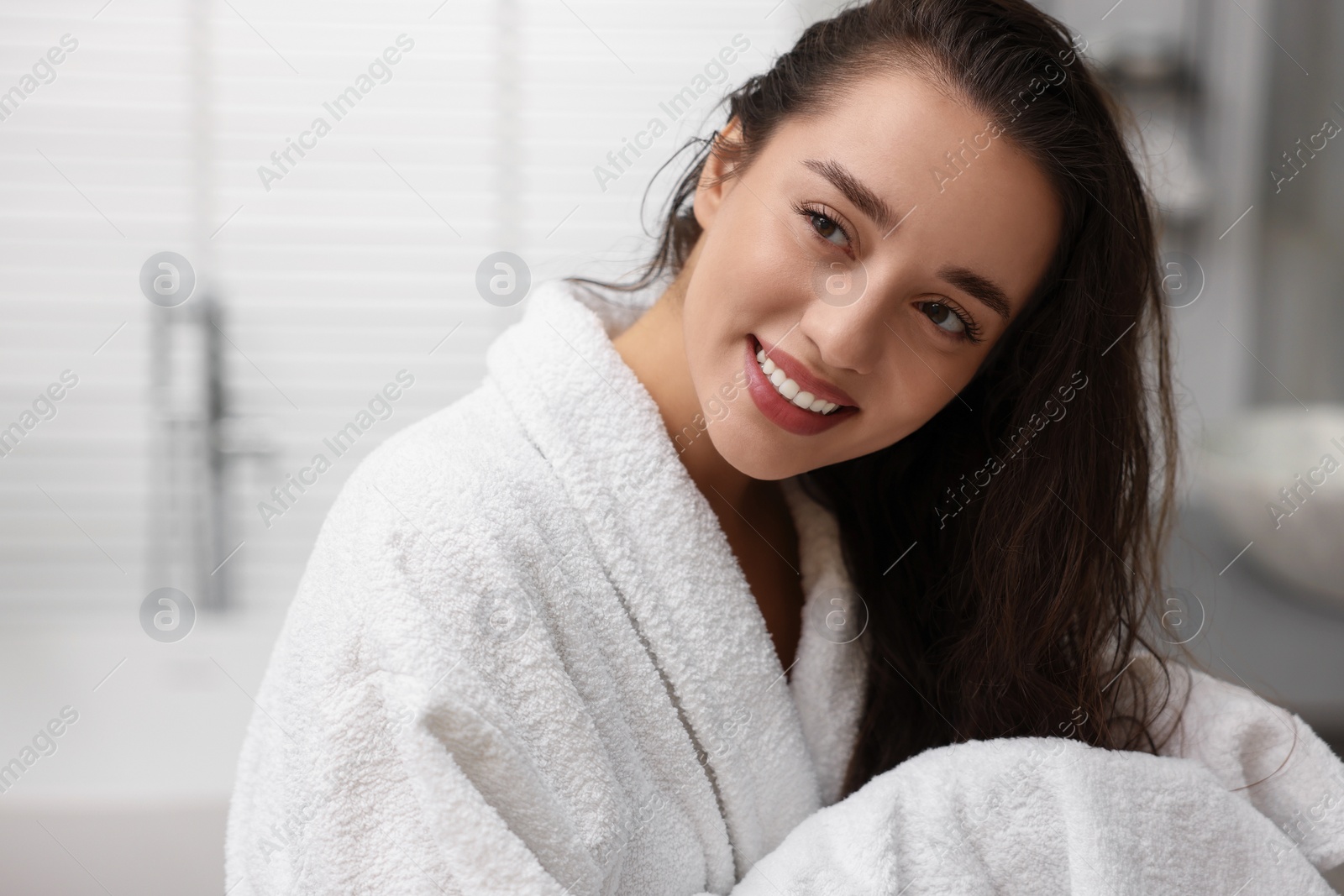 Photo of Smiling woman drying hair with towel after shower in bathroom