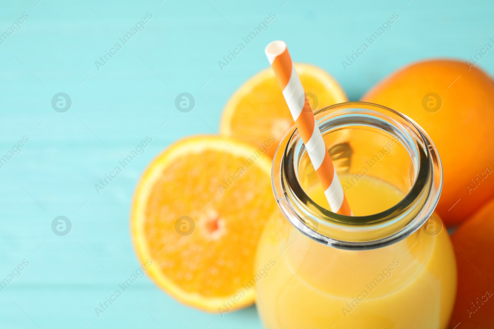 Photo of Bottle of orange juice and fresh fruits on light blue wooden table, closeup