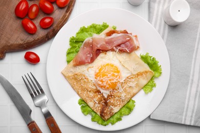 Delicious crepe with egg served on white tiled table, flat lay. Breton galette