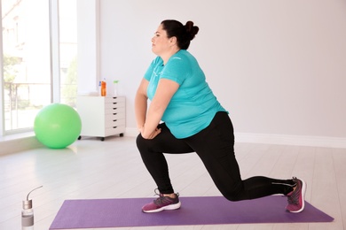 Photo of Overweight woman doing exercise on mat in gym