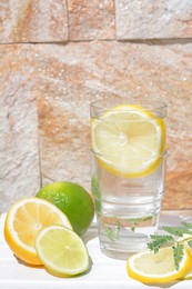 Photo of Delicious refreshing lemonade and pieces of citrus on white wooden table outdoors