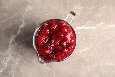 Tasty cranberry sauce in glass pitcher on table, top view