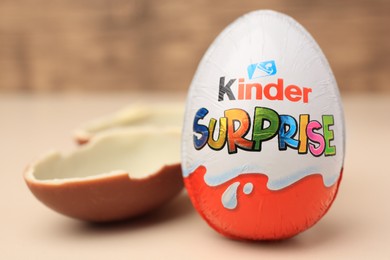 Photo of Slynchev Bryag, Bulgaria - May 25, 2023: Whole and broken Kinder Surprise Eggs on beige background, closeup. Space for text
