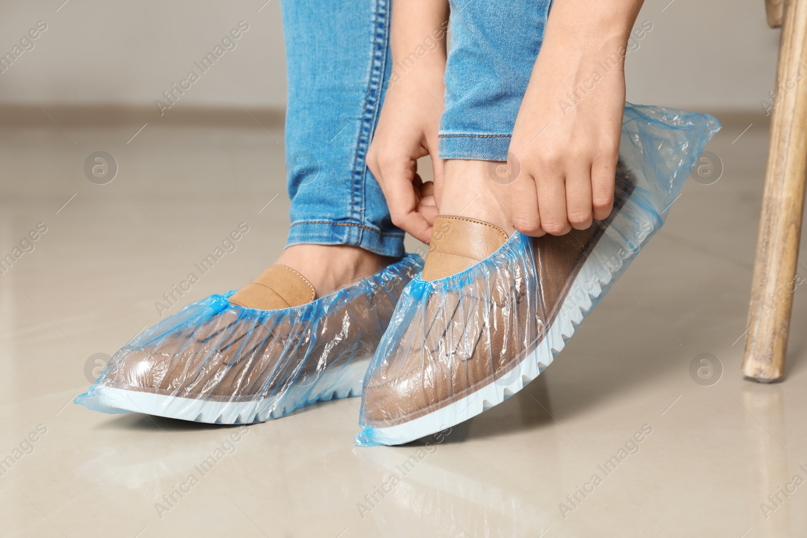 Photo of Woman putting on blue shoe covers, closeup