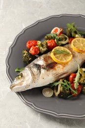 Photo of Baked fish with vegetables, rosemary and lemon on grey textured table