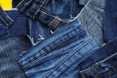 Photo of Many patches of old jeans on yellow background, top view