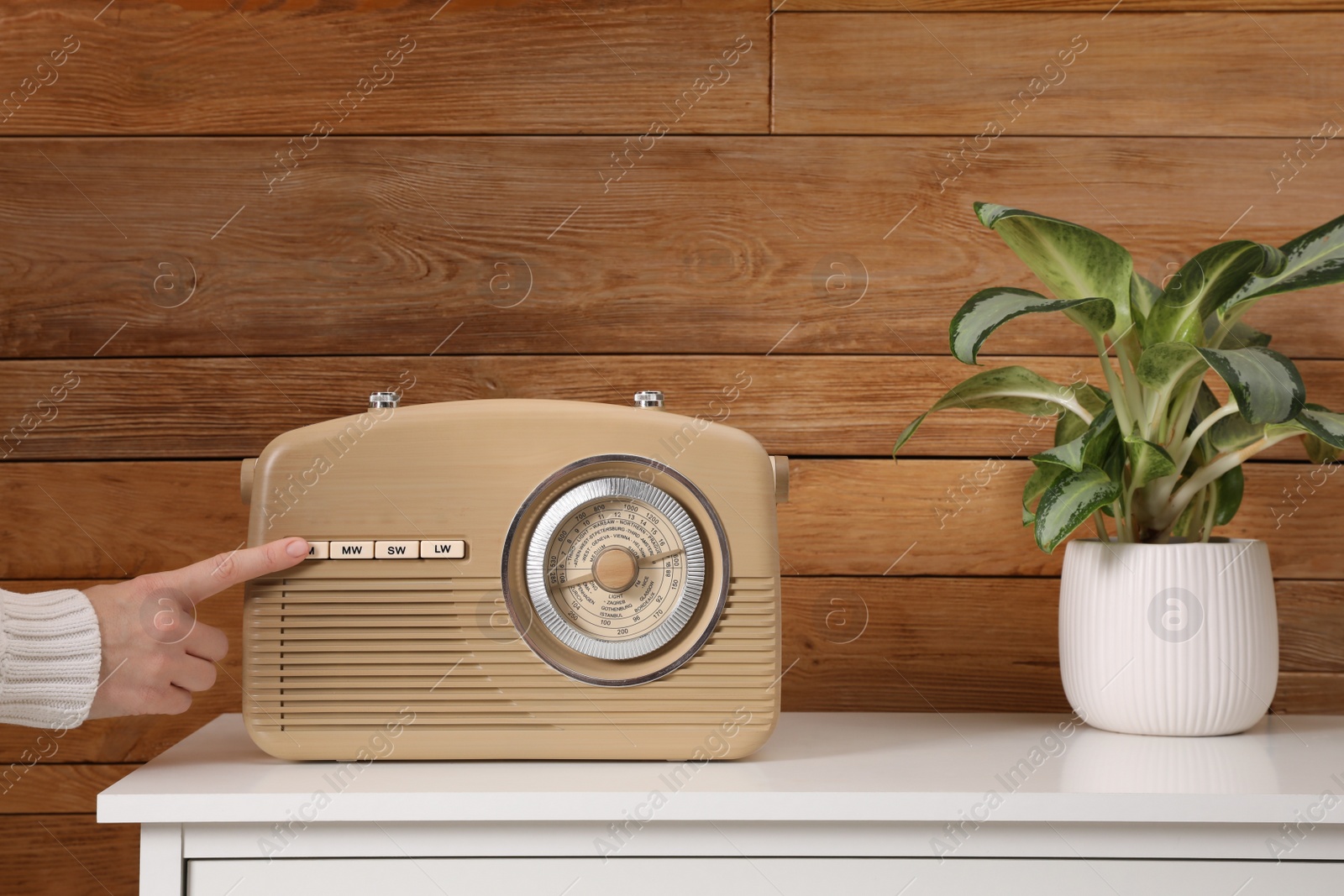 Photo of Woman pressing button on radio indoors, closeup