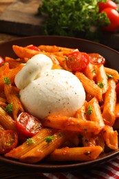 Delicious pasta with burrata cheese and tomatoes on table, closeup