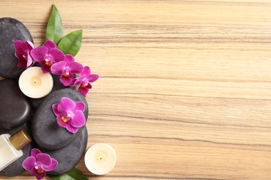 Flat lay composition with spa stones and orchid flowers on wooden background. Space for text