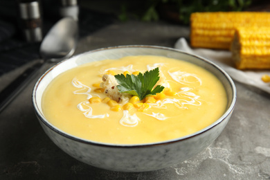 Delicious corn cream soup served on grey table, closeup