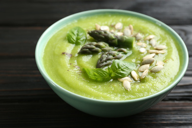 Delicious asparagus soup in bowl on black wooden table