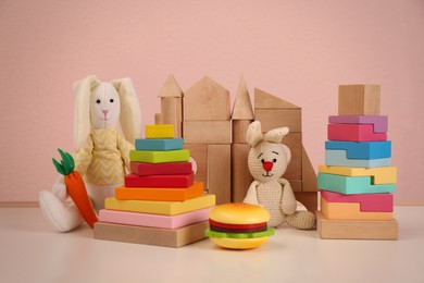 Set of different cute toys on wooden table against pink background