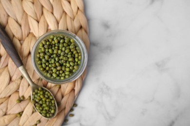 Photo of Glass jar of mung beans with spoon on white marble table, top view. Space for text