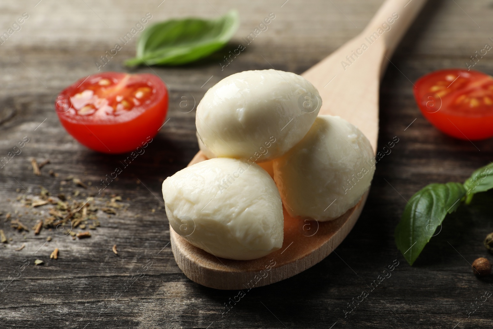 Photo of Delicious mozzarella balls, tomatoes and basil leaves on wooden table, closeup