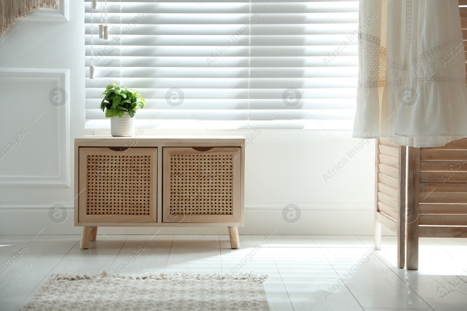 Photo of Wooden commode near window in room. Interior design