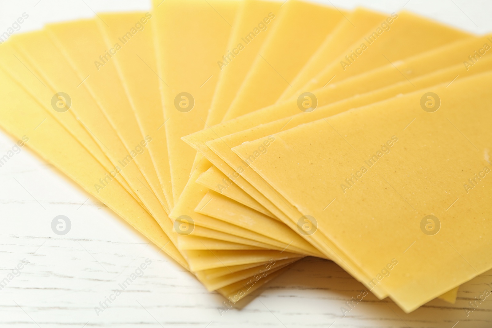 Photo of Uncooked lasagna sheets on white wooden table, closeup