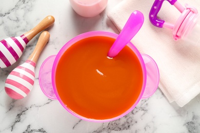 Photo of Flat lay composition with bowl of healthy baby food on white marble table