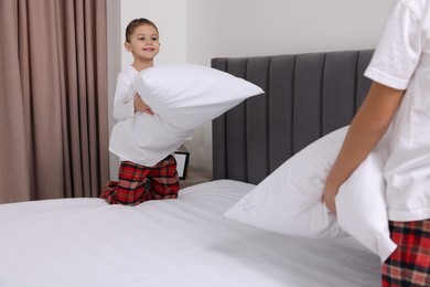 Brother and sister changing bed linens together in bedroom