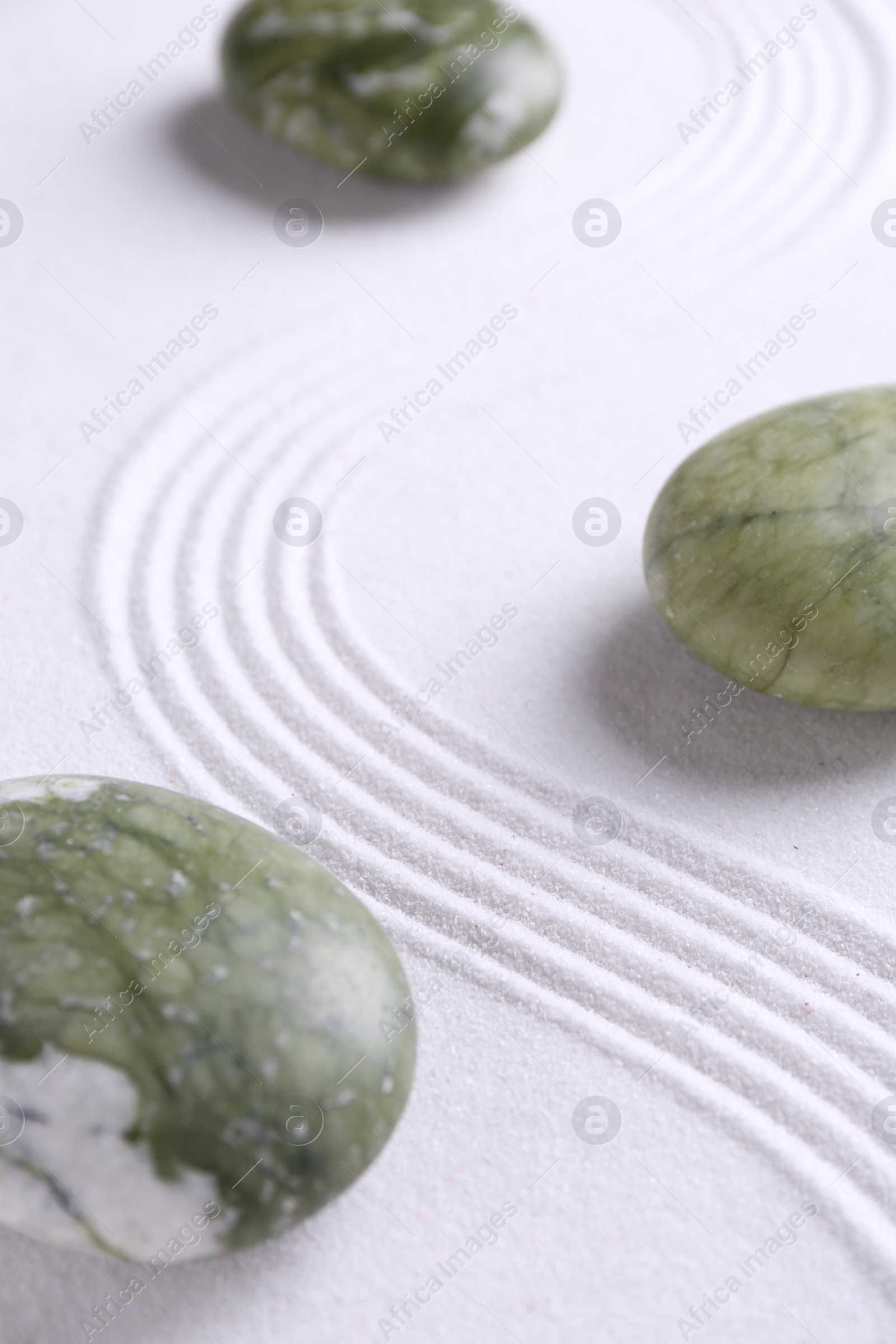 Photo of Zen concept. Stones and pattern on white sand, closeup