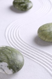 Photo of Zen concept. Stones and pattern on white sand, closeup