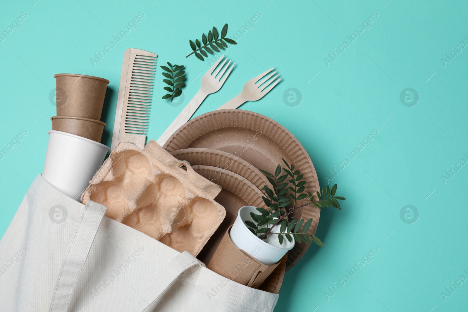 Photo of Eco bag with different disposable items on turquoise background, flat lay. Recycling concept