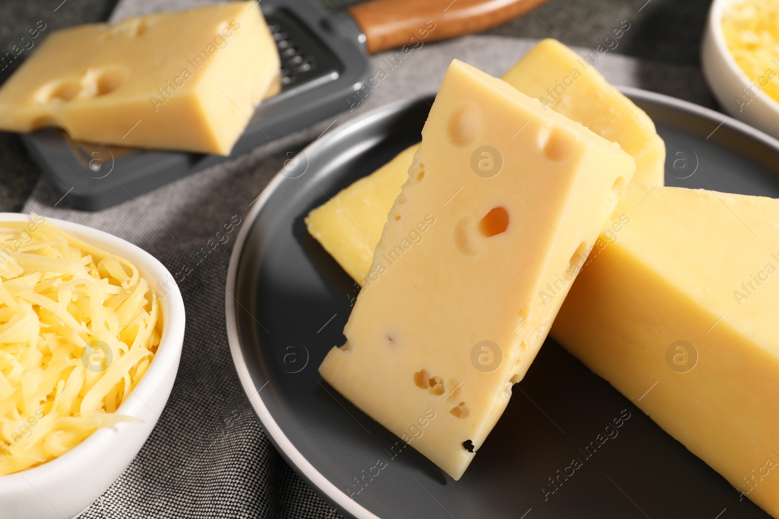 Photo of Grated and whole pieces of cheese on table, closeup